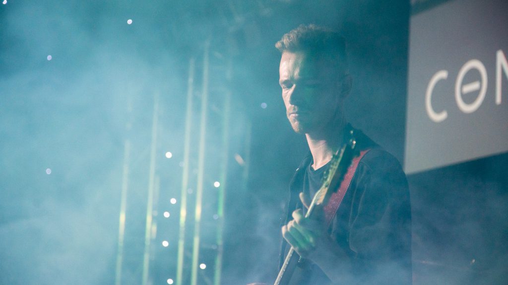 Bassist playing on a misty stage with lighting.