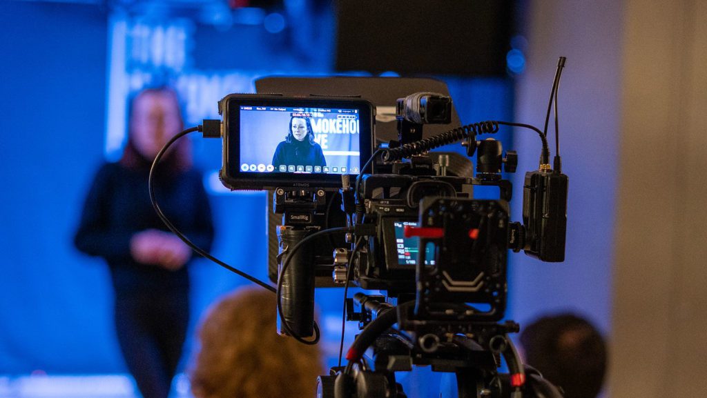 Video production of a lady on a stage talking.