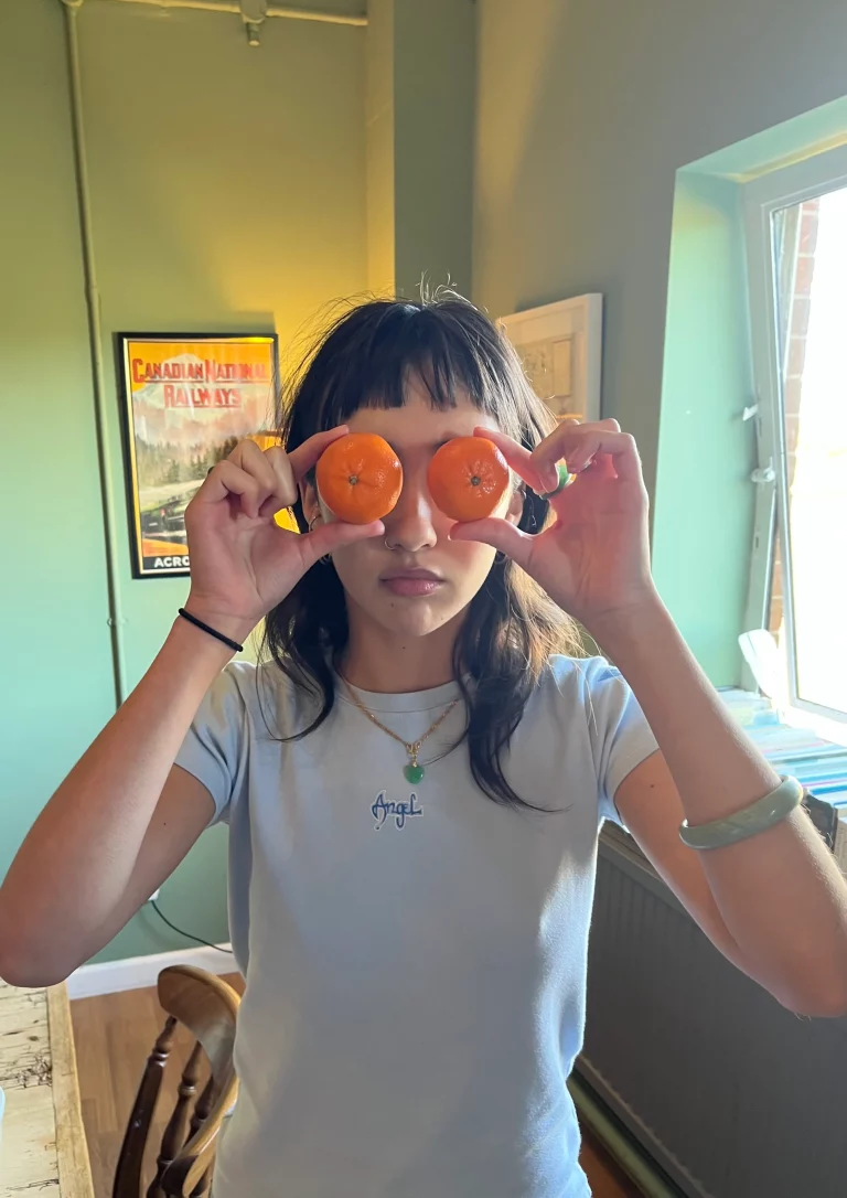 Young woman holding oranges in front of her eyes.