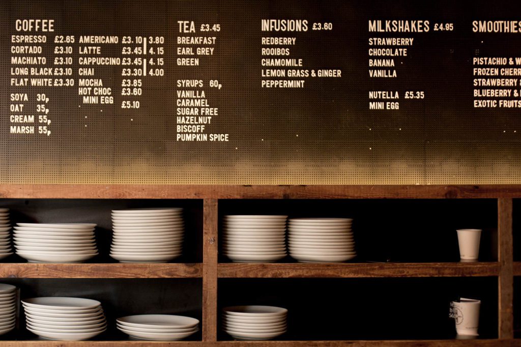Photograph of a cafe menu with plates stacked below.